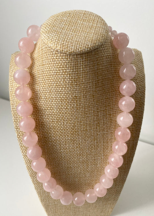 Aureline Rosé Rosenquarz Set — Zartes Rosenquarz‑Set aus Halskette und Armband mit runden, hellrosa Naturstein‑Perlen, präsentiert auf einer beigen Schmuckbüste in minimalistischem Stil.