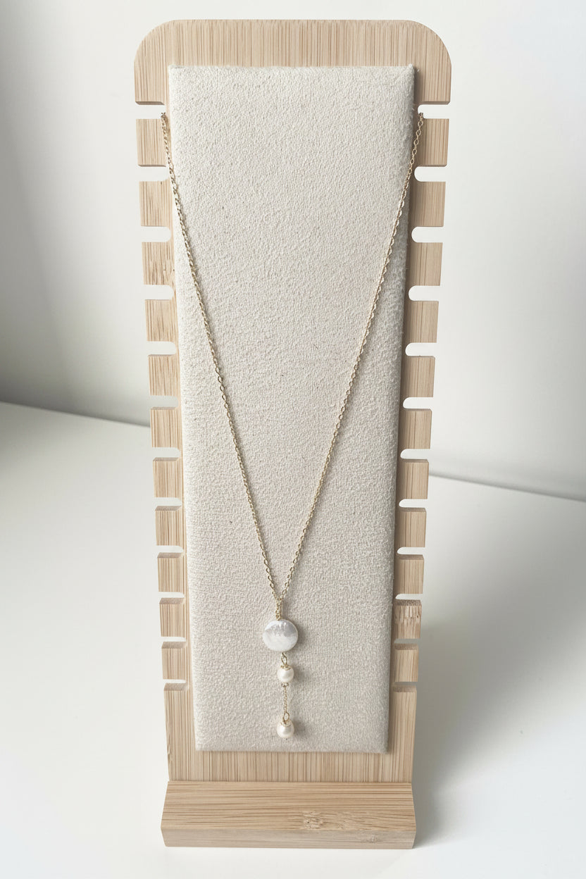 Merelle Pearl Fabienne Süsswasserhalskette mit feiner goldfarbener Kette und drei weissen Süsswasserperlen in vertikaler Anordnung, präsentiert auf einem minimalistischen Stoff‑Schmuckständer.