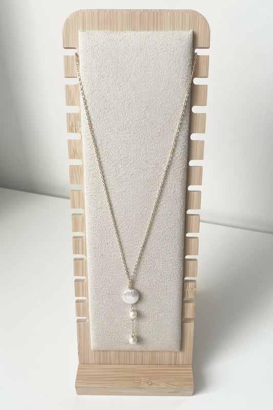Merelle Pearl Fabienne Süsswasserhalskette mit feiner goldfarbener Kette und drei weissen Süsswasserperlen in vertikaler Anordnung, präsentiert auf einem minimalistischen Stoff‑Schmuckständer.
